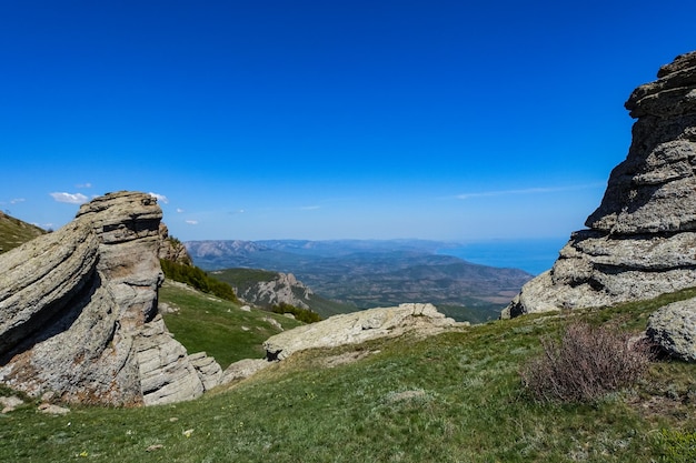 Hautes montagnes calcaires anciennes de forme arrondie dans la brume de l'air. La vallée des fantômes. Demerji. Arbres verts et buissons au premier plan. Mai 2021. Crimée.