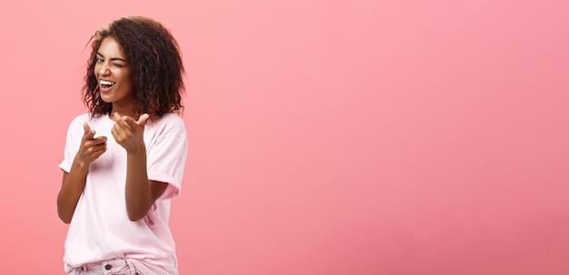 Hé, tu es une fille à la mode, à la peau noire, à la coiffure bouclée, joueuse, charmante et heureuse.