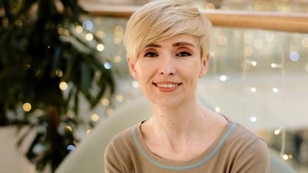 Head shot Caucasian woman blonde d'âge moyen avec un court sourire à l'intérieur des dents blanches regarde l'appareil photo