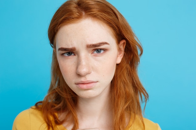 Headshot Portrait d&#39;adolescent roux tendre avec une expression sérieuse regardant la caméra. Modèle de femme caucasienne avec des cheveux au gingembre posant à l&#39;intérieur. Fond bleu pâtissier. Espace de copie.