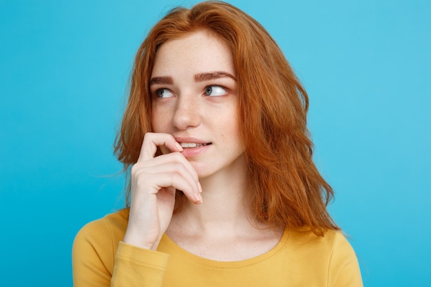 Headshot Portrait d&#39;une fille heureuse de gingembre aux cheveux roux avec des taches de rousse en regardant la caméra. Fond bleu pastel. Espace de copie.