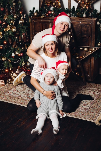 Héhé en chapeaux de père Noël rouge à l'arbre de Noël.