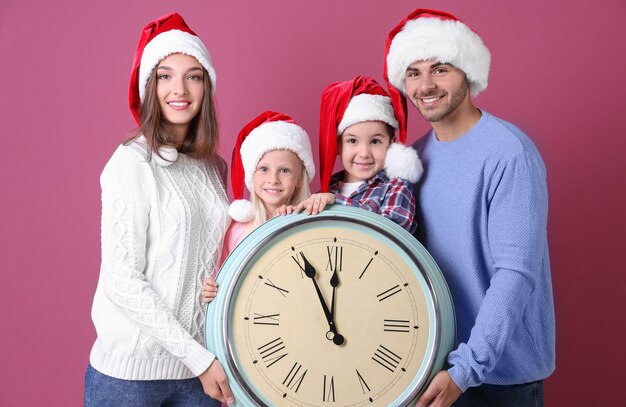 Héhé dans les chapeaux de Santa avec horloge sur le mur de couleur. Concept de compte à rebours de Noël