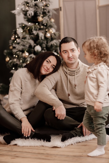Héhé, maman, papa et petite fille près de l'arbre de Noël à la maison.