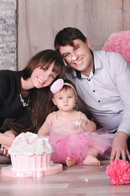 Héhé - mère, père et fille célébrant le premier anniversaire avec un gâteau.