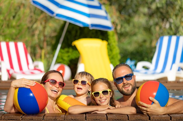 Héhé, s'amuser en vacances d'été. Père, mère et enfants jouant dans la piscine. Concept de mode de vie sain et actif