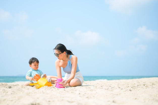 Héhé se reposant à la plage en été, mère et bébé pieds à la mer mousse à la lumière du soleil l'eau se déplace