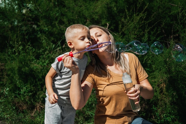 Héhé, soufflant des bulles de savon dans le jardin de l'arrière-cour enfant enfant garçon soufflant des bulles de savon heureux