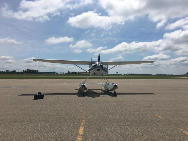 Hélicoptère sur piste à l'aéroport contre un ciel nuageux