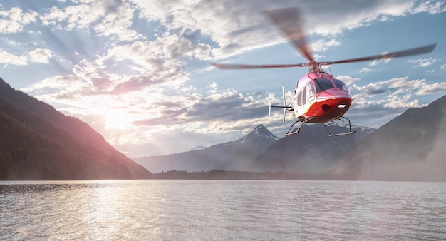 Hélicoptère survolant un lac, des arbres et des montagnes dans le paysage canadien