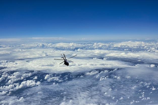 Hélicoptère volant sur fond de nuages et de ciel bleu. Petit avion