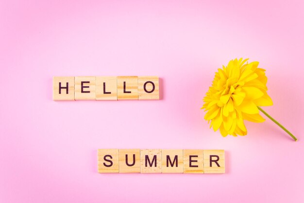 Hello summer concept Fleur jaune sur fond rose Lettrage en bois