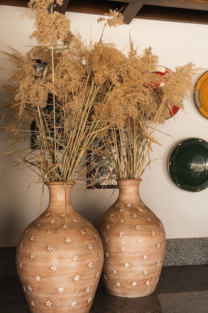 Herbe de la pampa, roseaux dans des pots en argile. Design d'intérieur oriental traditionnel avec des plaques ornementales colorées