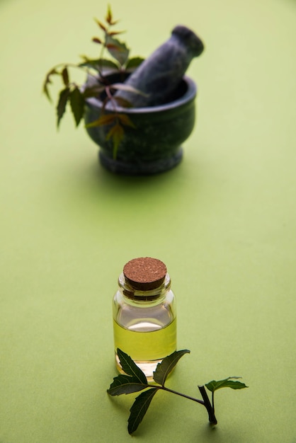 Herbes antibactériennes ayurvédiques Neem ou Lilas ou Azadirachta indica avec de l'huile en bouteille avec du mortier, isolées sur fond uni, mise au point sélective