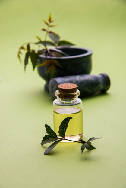 Herbes antibactériennes ayurvédiques Neem ou Lilas ou Azadirachta indica avec de l'huile en bouteille avec du mortier, isolées sur fond uni, mise au point sélective