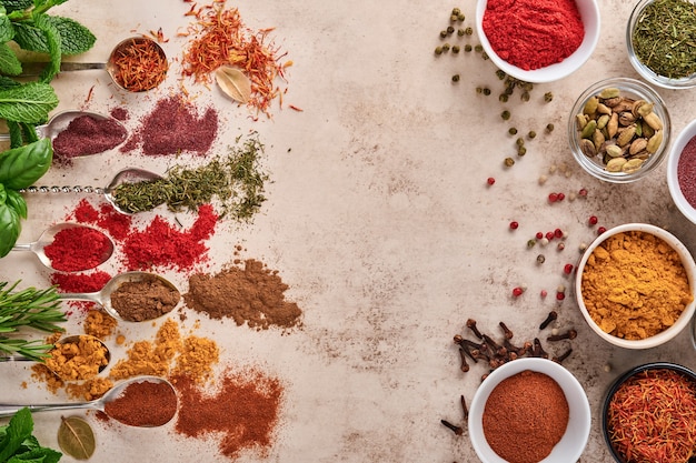 Herbes et épices colorées pour cuisiner sur une surface en pierre brun clair. Vue de dessus.