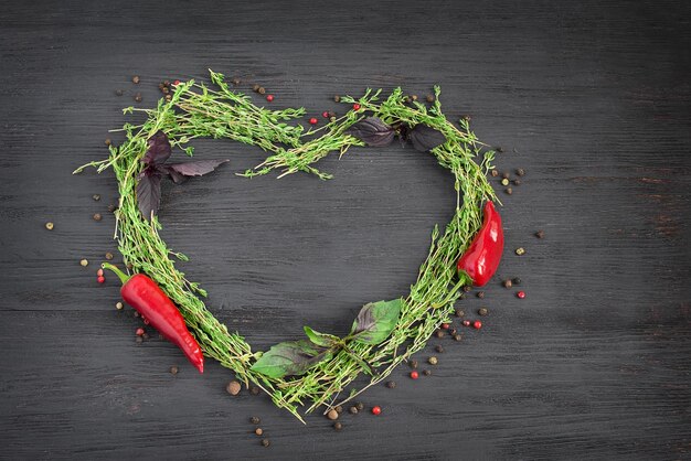 Herbes et épices de thym frais disposées en forme de coeur sur fond sombre