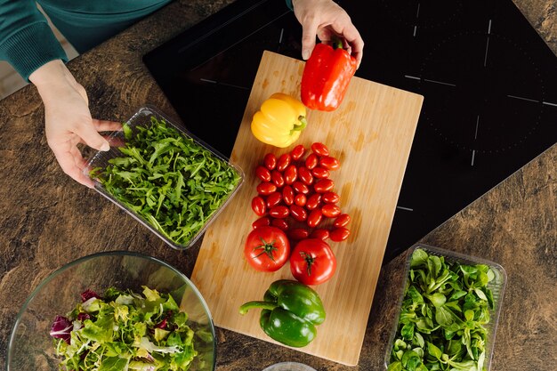 Herbes fraîches mains d'une femme au foyer. maman femme prépare une salade de légumes frais et verts tomates cerises rucola poivron. vie domestique. concept d & # 39; aliments sains