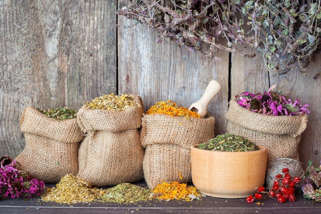 Herbes médicinales séchées dans des sacs de jute et dans du mortier sur fond de mur en bois phytothérapie