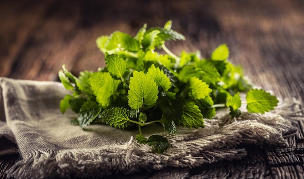 Herbes de mélisse naturellement vertes sur une serviette rustique en jute ou en lin pliée sur du bois foncé