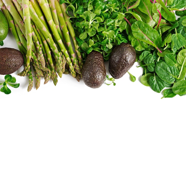 Herbes vertes, asperges et avocat noir sur fond blanc. Vue de dessus.