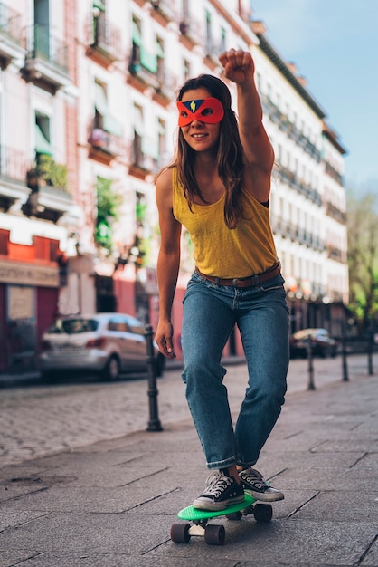 Héroïne de femme moderne avec masque dans une planche à roulettes. Super-héros.