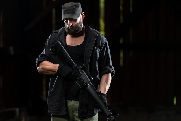 Héros d'action homme musclé tenant une mitrailleuse debout dans un bâtiment abandonné portant un pantalon vert