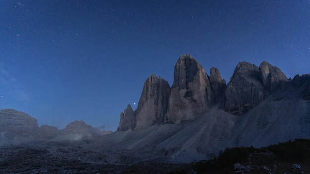 L'heure bleue et les premières étoiles apparaissent au-dessus d'énormes montagnes rocheuses tre cime dolomites italie