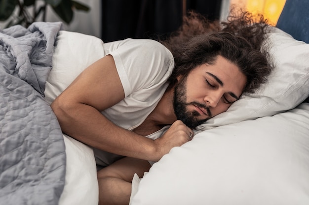 L'heure de dormir. Agréable bel homme allongé sur l'oreiller en voulant dormir