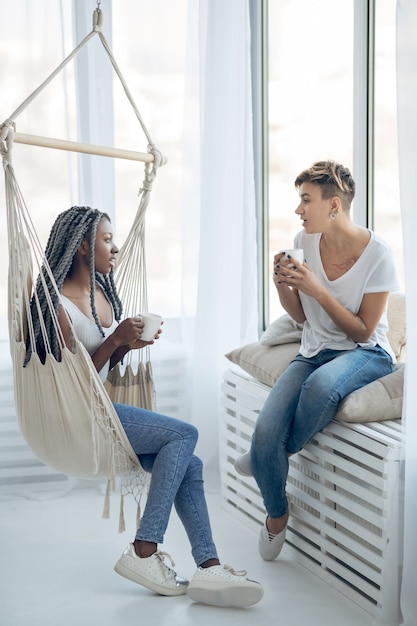 L'heure du café. Deux filles prenant un café dans une pièce lumineuse et parlant