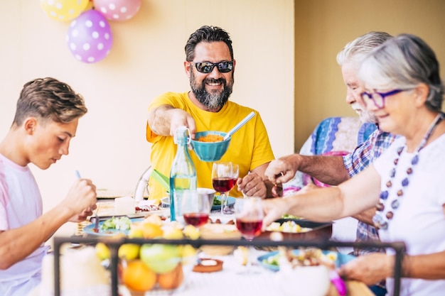 Heure du déjeuner Famille caucasienne appréciant la nourriture et les boissons Quatre personnes Trois générations Table en bois sur le terrain de la terrasse