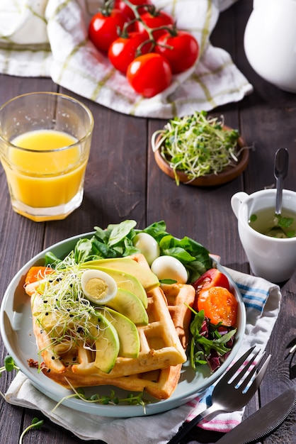 L'heure du déjeuner. Gaufre avec salade, œuf, jus et avocats pour le petit déjeuner