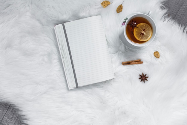 Photo l'heure du thé avec un cahier sur un tapis blanc