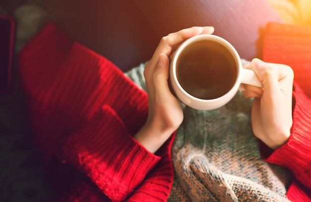 L'heure du thé le matin Mains de femme tenant une tasse de thé dans la lumière du soleil du matin