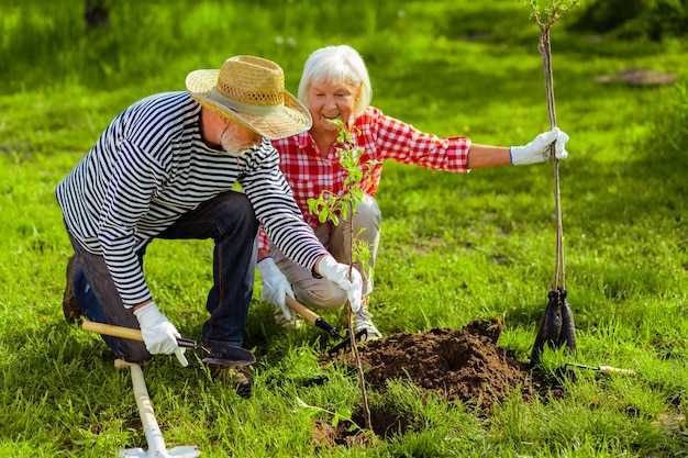 Heure d'été. Beau beau mari et femme vivant dans une maison de campagne en été plantant des arbres