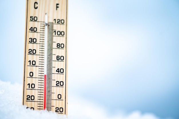 L'heure d'hiver Thermomètre sur neige avec arrière-plan flou montre de basses températures Celsius et farenheit