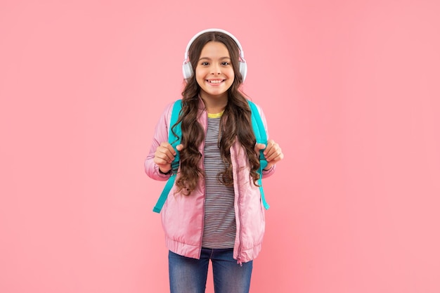 Heureuse adolescente dans les écouteurs. écouter de la musique. accessoire de casque sans fil. nouvelle technologie. développement de l'enfance. enfant dans des écouteurs modernes avec sac à dos. éducation en ligne. retour à l'école.