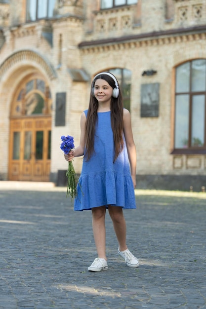 Heureuse adolescente dans les écouteurs fille debout en plein air sur toute la longueur de la fille