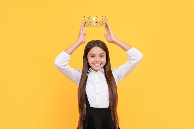 Heureuse adolescente égoïste en uniforme scolaire porter l'égoïsme de la couronne de princesse