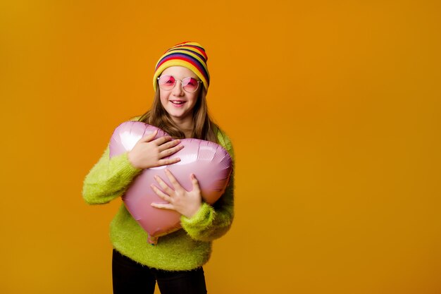 Heureuse adolescente à lunettes de soleil est titulaire d'un ballon en forme de coeur