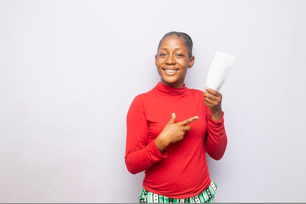 Heureuse adolescente noire pointant un doigt sur le papier à la main