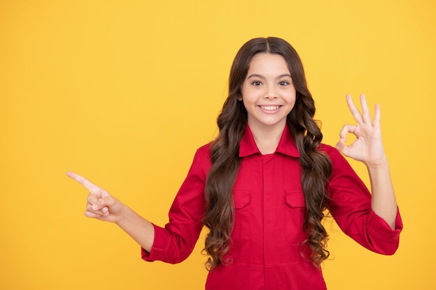 heureuse adolescente pointant le doigt sur l'espace de copie avec un geste ok, publicité.