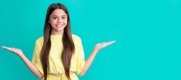 Heureuse adolescente présentant le produit faisant le choix sur fond bleu avec choix d'espace de copie Visage d'enfant affiche horizontale adolescente portrait isolé bannière avec espace de copie