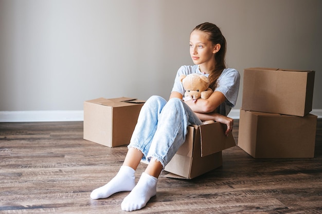 Heureuse adorable fille avec des boîtes en carton dans une nouvelle maison le jour du déménagement