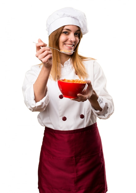 Heureuse belle chef femme mangeant des céréales dans un bol