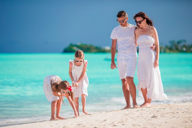 Heureuse belle famille en blanc sur la plage