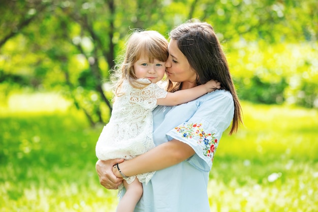 Photo heureuse belle famille ensemble mère et fille portrait sur l'herbe par une journée d'été ensoleillée