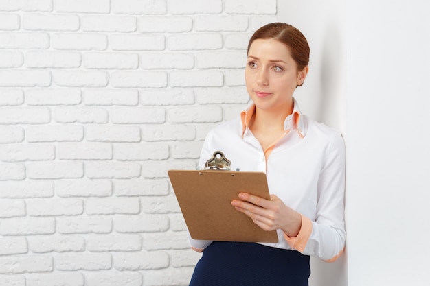 Heureuse belle femme d&#39;affaires avec le presse-papier au bureau.