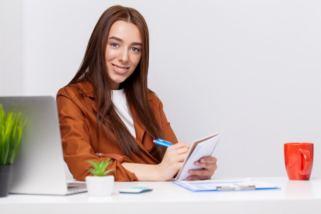 Heureuse belle femme d'affaires avec presse-papiers au bureau.