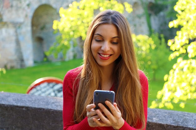 Heureuse belle femme à l'aide de l'application de téléphone intelligent